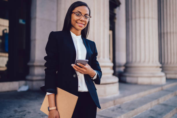 Professional woman holding phone and documents representing career success